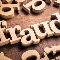 Letter blocks that spell out fraud on top of table Letter blocks that spell out fraud on top of table