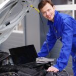Mechaniker arbeitet mit einem Laptop an einem Auto, Motorsteuerung