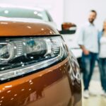 Young couple buying a new car in dealership