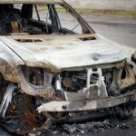 A car after a fire, close-up. A blown-up and burnt-out SUV on a city street. Criminal showdowns of gang groups.