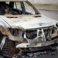 A car after a fire, close-up. A blown-up and burnt-out SUV on a city street. Criminal showdowns of gang groups.