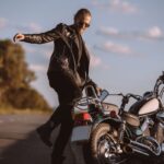 angry man kicking broken motorbike on road