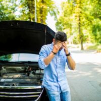 Young man on the road having problem with a car. Broken down car on the road. Traveling problem in road.