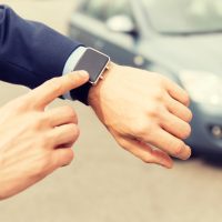 close up of male hands with wristwatch and car