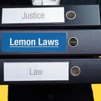 Lemon Laws. Lawyer (man) carries a stack of folders. 3 file fold