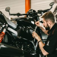 Professional mechanic working screwdriver and motorcycle repairs. Handsome young man repairing motorcycle in repair shop.