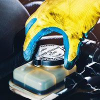 The mechanic hand is open or close the cap of the power steering fluid to check the hydraulic fluid level