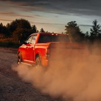 Pickup truck car in motion at country road with clouds of dust