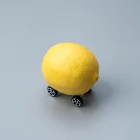 A lemon with small wheels attached to it. Lemon car, defect or malfunction car concept.