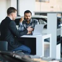 Car salesman discussing financing with customer at dealership
